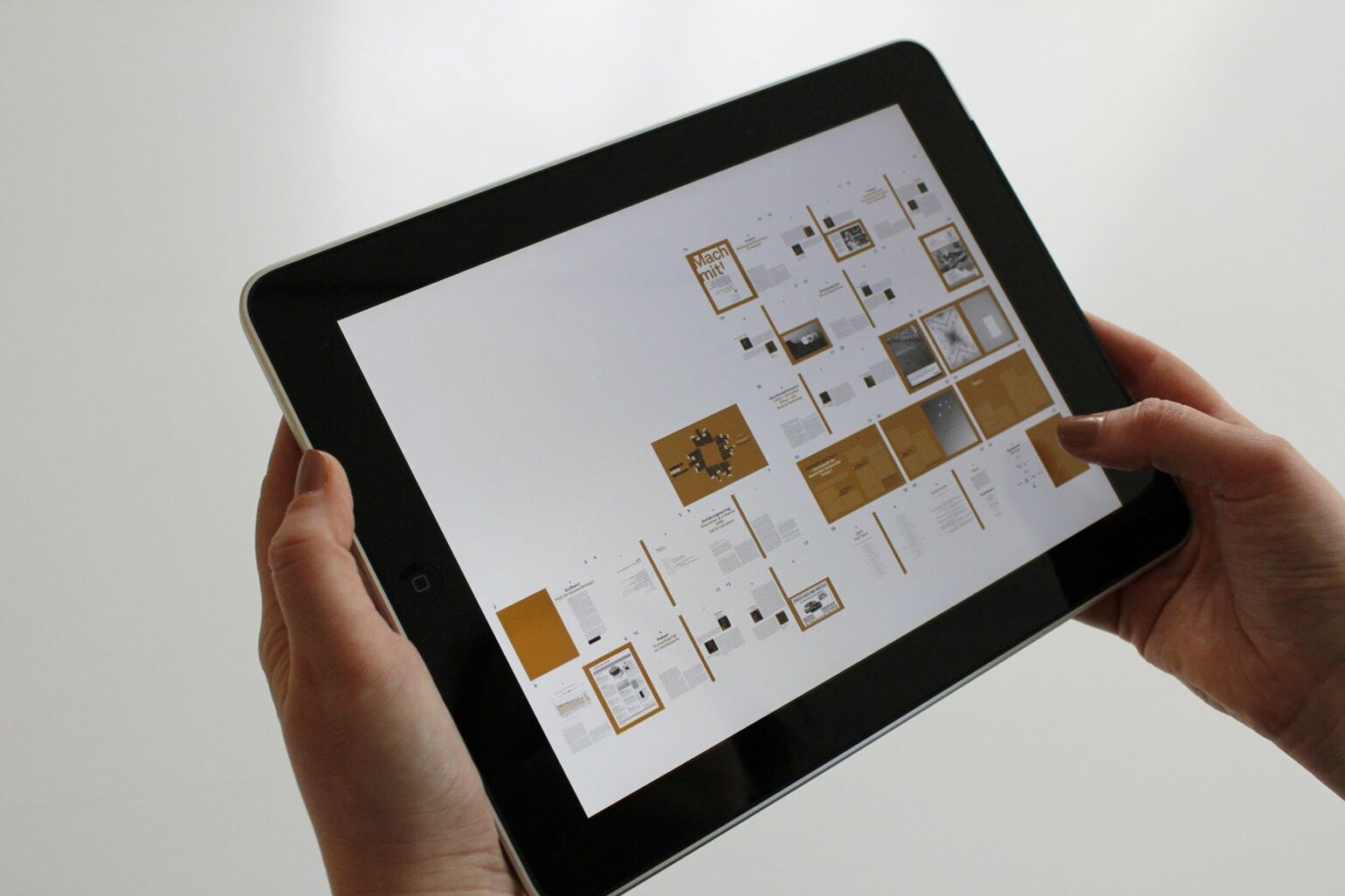Tablet trzymany w dłoniach. Na wyświetlaczu grafiki i schematy / Digital tablet held in hands. Charts and figures visible on the screen