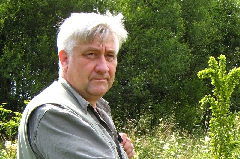 Prof. dr hab. Adam Rostański trzymający roślinę na polanie / Prof. Adam Rostański holding a plant on a clearance