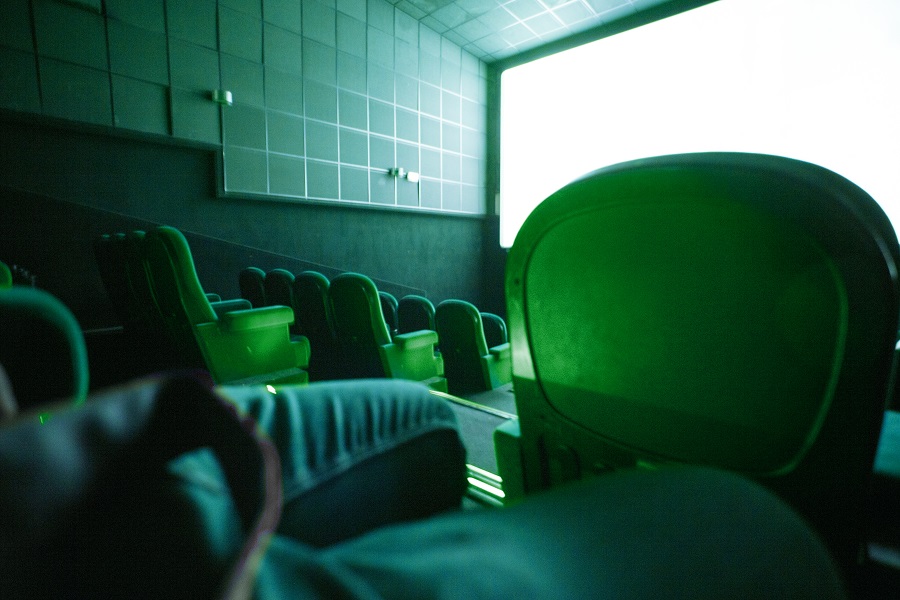 sala kinowa z białym ekranem i zielonymi krzesłami