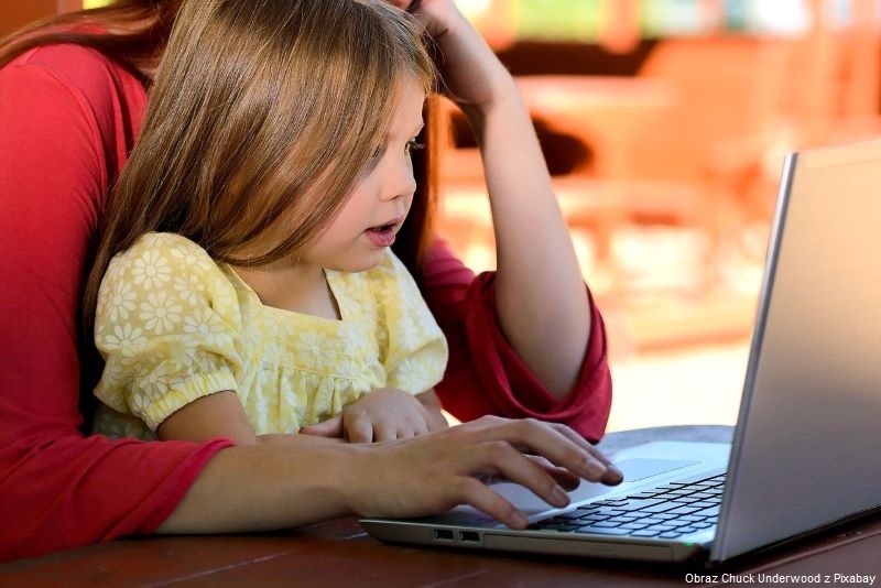 Dziewczynka z osobą dorosłą korzystają z komputera