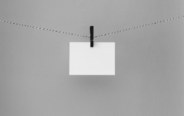 biała kartka przypięta czarnym klipsem na sznurka / blank piece of paper hanging on a string