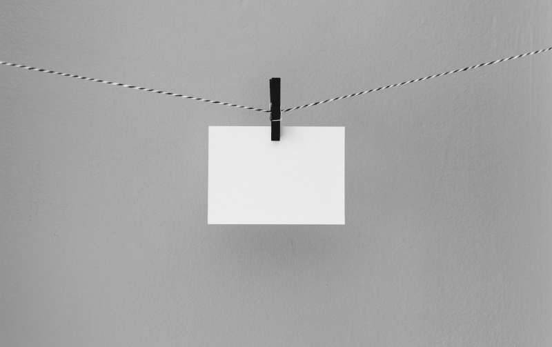 biała kartka przypięta czarnym klipsem na sznurka / blank piece of paper hanging on a string