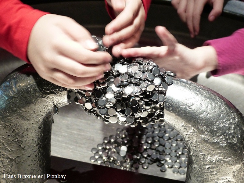 Dzieci przeprowadzają eksperyment z magnesami, na zdjęciu widać ręce dzieci i magnesy