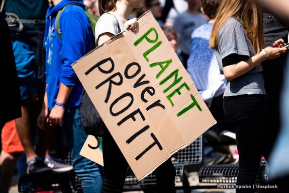 Widok na trzymany w ręce karton z hasłem „Planet over profit” trzymany przez dziewczynę w tłumie / "Planet over profit" transparent held by a girl in the crowd