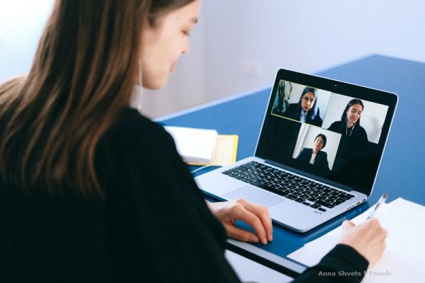Dziewczyna siedzi przed laptopem, na którym wyświetla się widok z kamer trzech osób, z którymi prowadzi konwersację