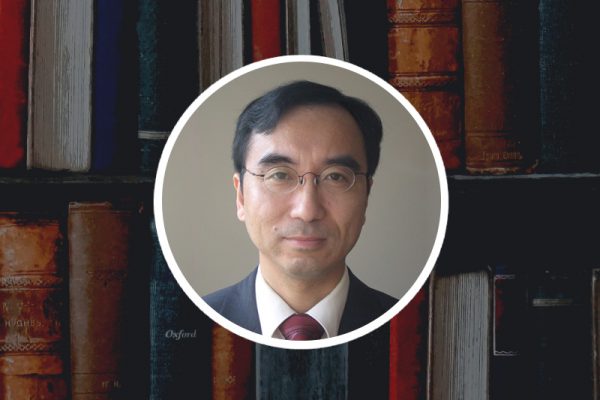 Zdjęcie portretowe prof. Zhendonga Jina, w tle regał z książkami 