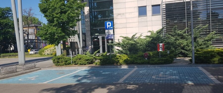 Widok na 3 miejsca parkingowe dla osób niepełnosprawnych zlokalizowanych przed wejściem do budynku.