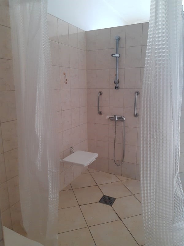 Wnętrze prysznica z krzesełkiem prysznicowym i uchwytami.