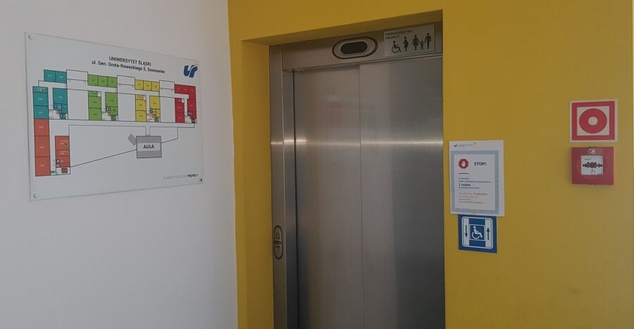 Wyjście z windy. Na ścianie wisi plan budynku./Exit from the lift. There is a building plan on the wall.