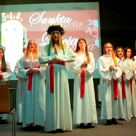 orszak złożony ze studentek w białych szatach, śpiewających pieśń „Sankta Lucia”
