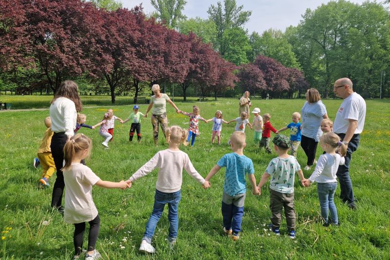 dzieci trzymające się za ręce tworząc koło w parku