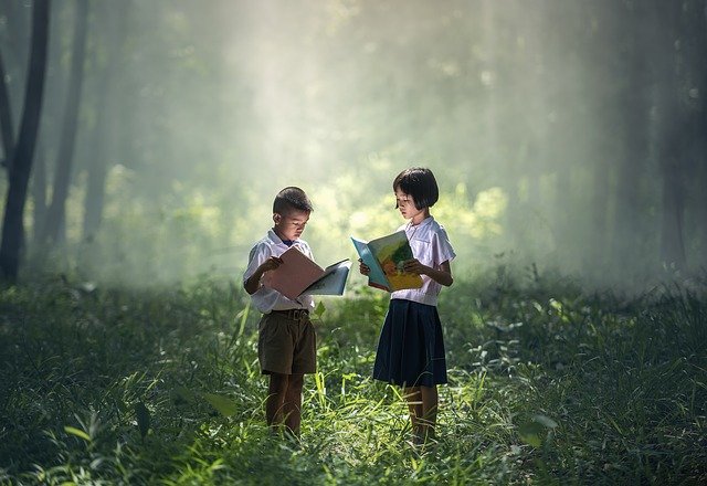 dzieci stojące w lesie i czytające książki