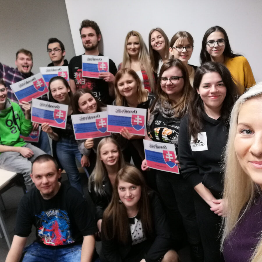 grupa studentów trzymających w dłoniach małe flagi Słowacji