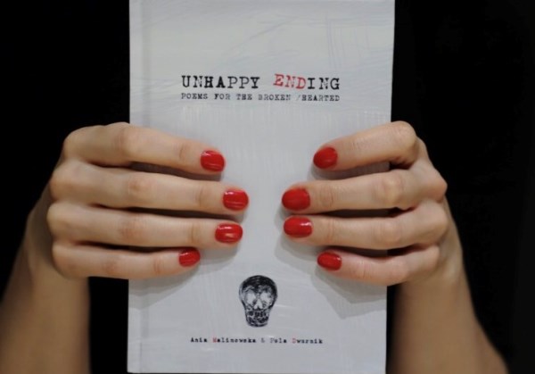 zbliżenie na dłonie kobiety trzymającej książkę pt. "Unhappy ending"