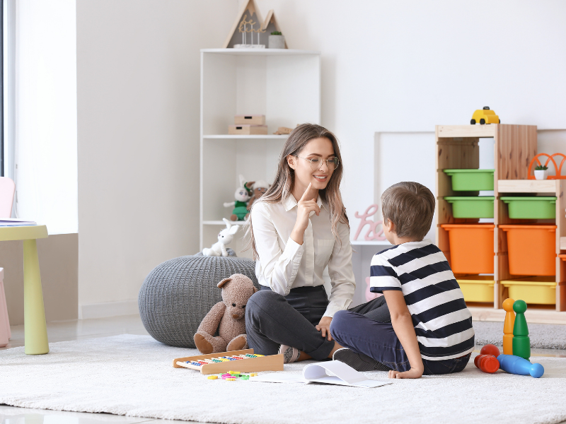 logopedka siedząca na dywanie wraz z dzieckiem podczas sesji terapeutycznej