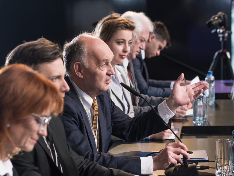 politycy wraz z tłumaczami zasiadający przy stole konferencyjnym