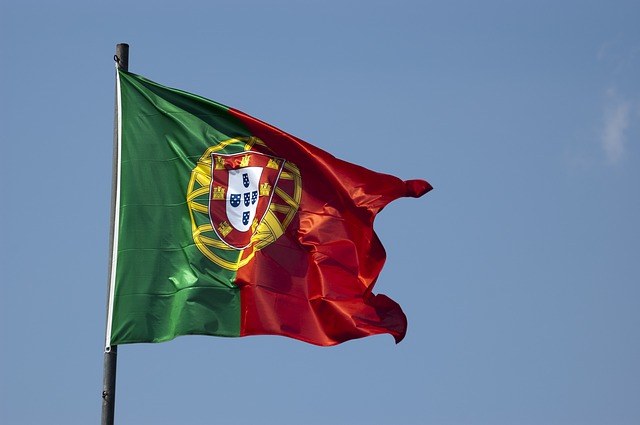 flaga Portugalii powiewająca na tle niebieskiego nieba