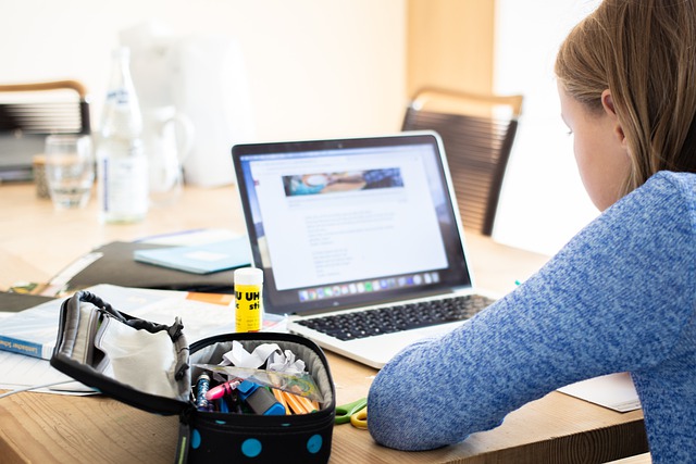 studentka siedząca przy stole przed otwartym laptopem