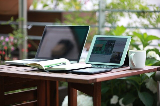 laptop i tablet leżące na stole obok otwartego notesu