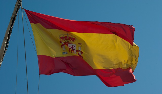 flaga Hiszpanii powiewająca na tle niebieskiego nieba