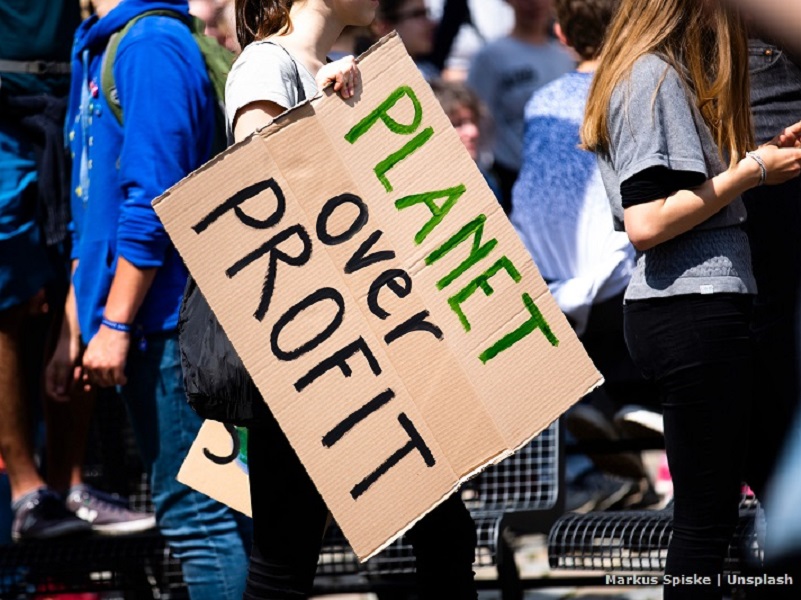 A group of people with a board: planet over profit