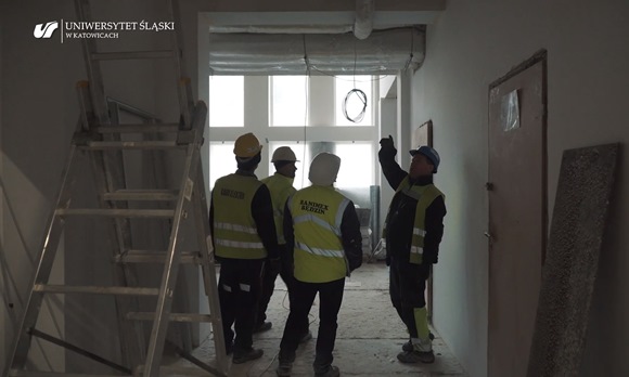 Czterej przedstawiciele wykonawcy robót budowlanych stojący w remontowanym korytarzu