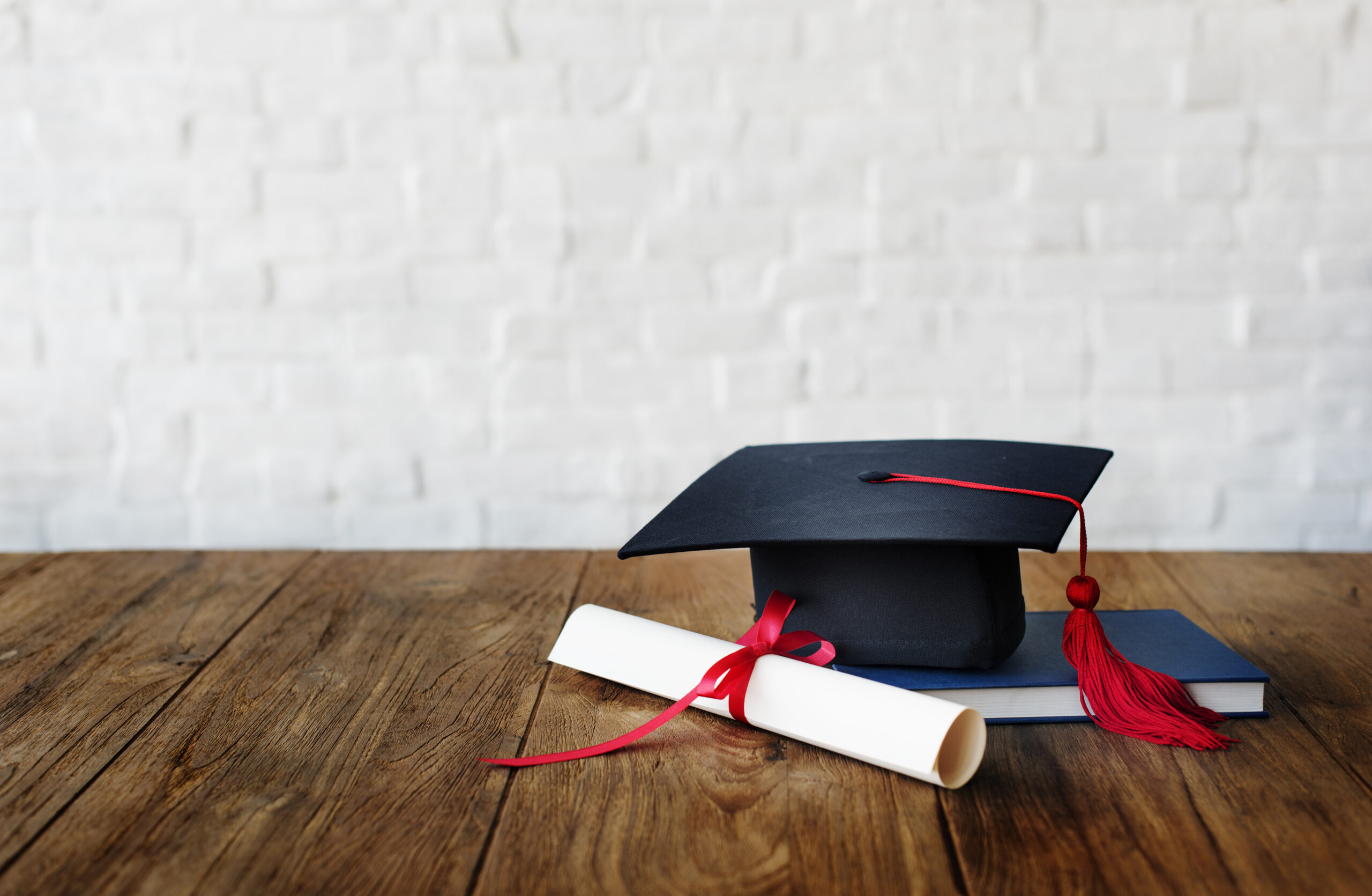 Zdjęcie czarnego biretu studenckiego oraz dyplomu przewiązanego kokardką