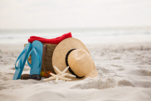 zdjęcie kapelusza słomkowego, klapek, torby i rozgwiazdy na piaszczystej plazy