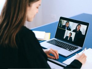 osoba siedząca przed laptopem podczas spotkania online).