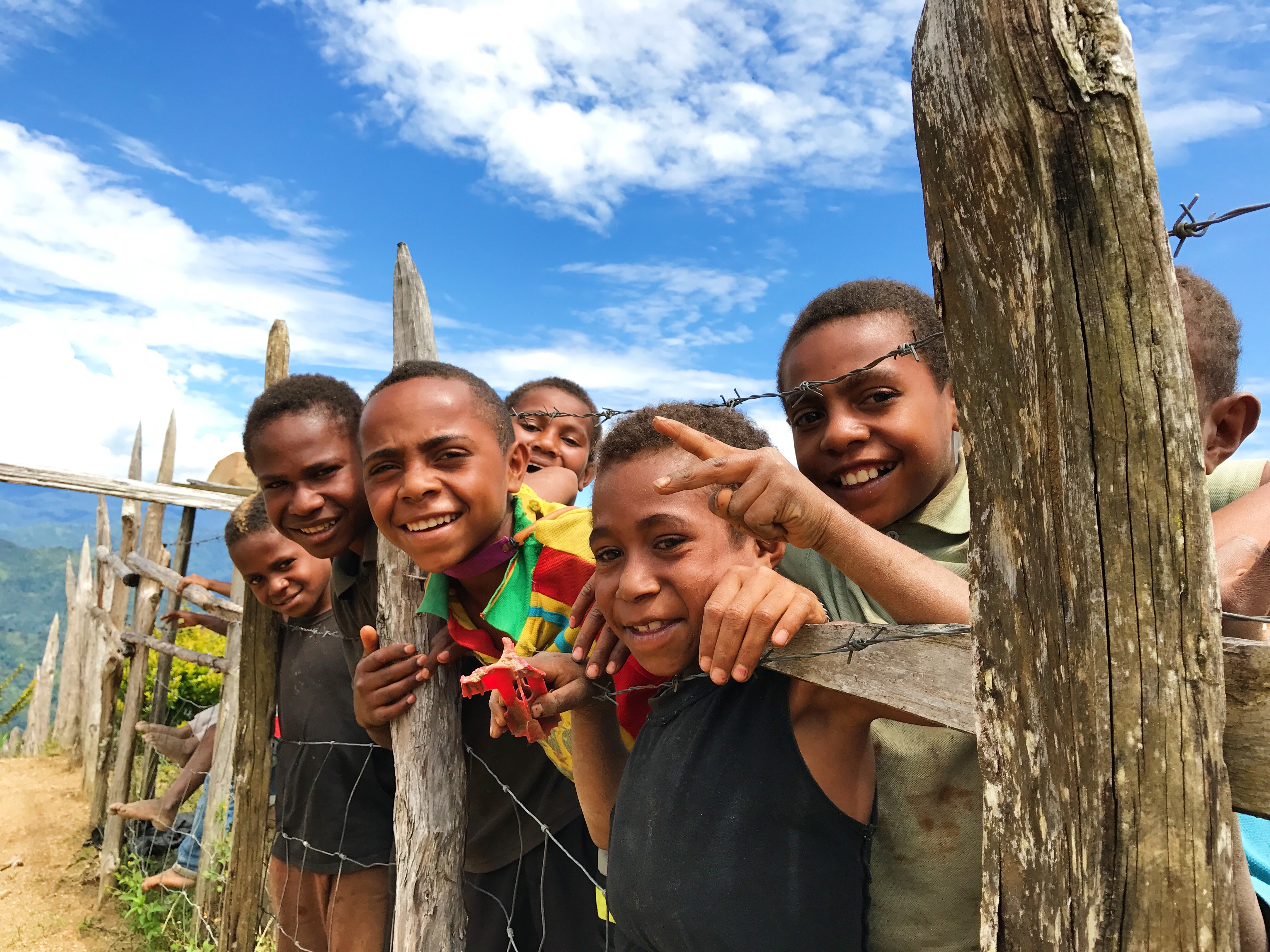 Grupa dzieci stojąca za drutem kolczastym