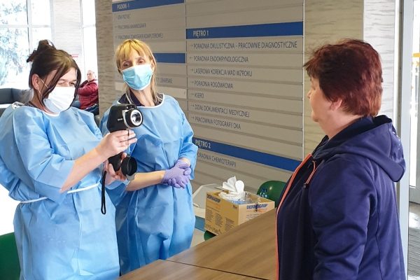 pracownik szpitala kamerą termowizyjną sprawdza temperaturę pacjenta