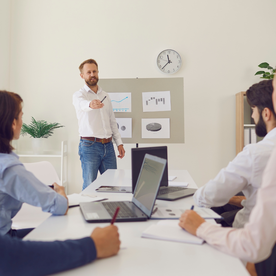 mężczyzna przemawia podczas spotkania do grupy pracowników siedzących przy stole